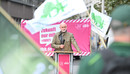 Ein Mann steht im Mittelpunkt des Bildes und spricht in ein Mikrofon
