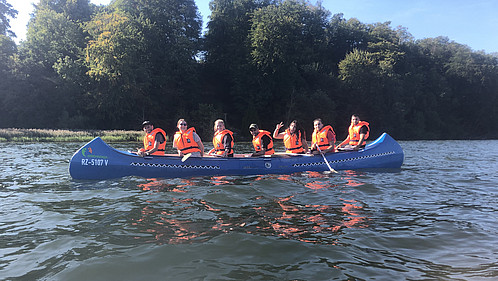 Das Foto zeigt eine Gruppe im Kanu auf dem Wasser.