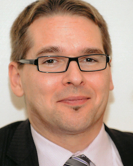 Ein Portrait von einem lächelnden Mann mit Brille.