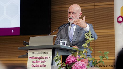 Ein Mann steht hinter einem Rednerpult und spricht in das Mikrofon