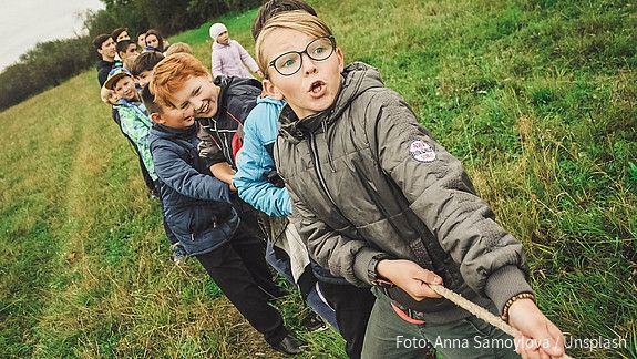 Kinder und Jugendliche ziehen an einem Seil
