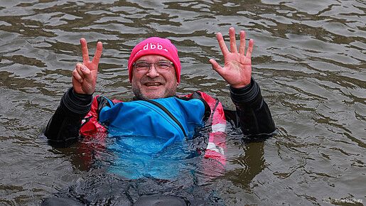 Ein Mann in Neoprenanzug badet in einem Fluss