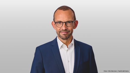 Foto von einem weißen Mann mit Anzug und Brille, der in die Kamera blickt. Es handelt sich um Thomas Röwekamp, Vorsitzender des Verteidigungsausschusses des Deutschen Bundestages 