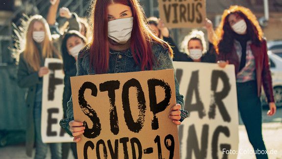 Frauen in Zeiten von Covid 19 Auf einer Demonstration halten Frauen mit Minde-Nasen-Schutz Plakate mit der Aufschrift "Stop Covid-19"