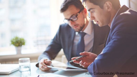 Digitalisierung Zwei Männer im Büro sehen gemeinsam auf Tablet und besprechen sich