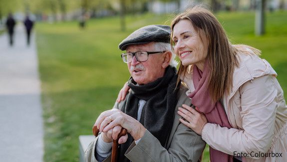 Das Foto zeigt einen glücken Senior mit seiner Tochter im Park.