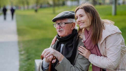 Das Foto zeigt einen glücken Senior mit seiner Tochter im Park.