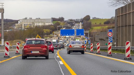 Zu sehen sind Autos auf einer Autobahn, rechts und links am Fahrbahnrand stehen Baustellen-Barken.