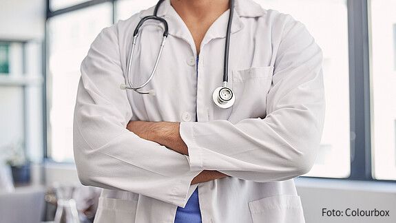 Das Foto zeigt einen Arzt, er hat die Arme verschränkt.