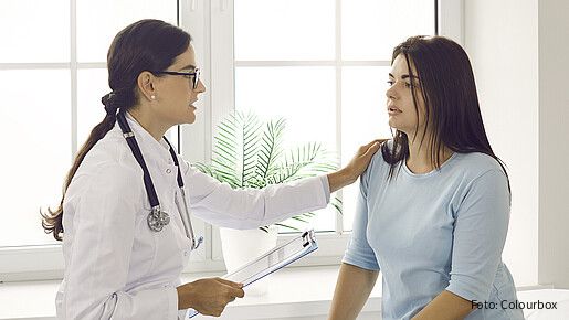Doctor talking to patient, comforting, supporting and reassuring her. Worried young woman having conversation with physician about health issues while sitting in exam room in modern clinic or hospital