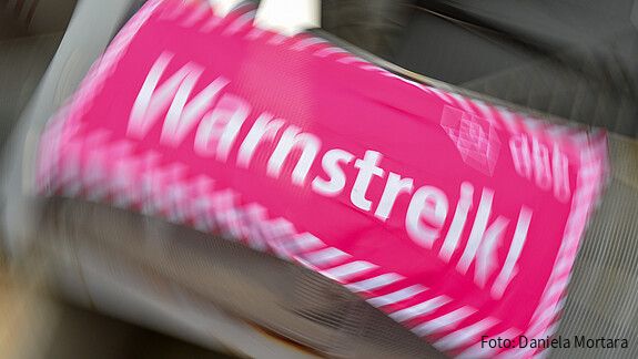 Foto eines neon-pinken Banners, auf dem in weißer Schrift "Warnstreik!" steht