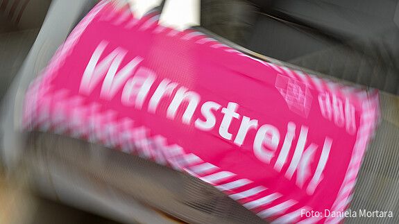 Foto eines neon-pinken Banners, auf dem in weißer Schrift "Warnstreik!" steht
