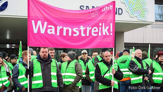 Das Foto zeigt demonstrierende Straßenwärter. Sie tragen grüne Streikwesten.
