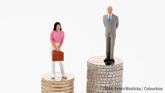 Das Foto zeigt eine männliche und eine weibliche Figur, die auf Münzstapeln stehen. Der Stapel der männlichen Figur ist deutlich höher.