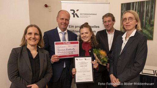 Fünf Menschen halten eine Urkunde für den ersten Platz und blicken in die Kamera