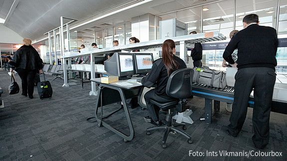 Das Bild zeigt Mitarbeitende des Sicherheitspersonals bei der Sicherheitskontrolle am Flughafen.