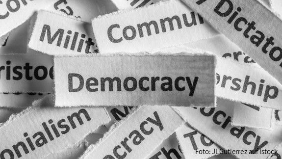 EWSA fordert Rücknahme der Richtlinie im Demokratiepaket Verschiedene Staatsformen sind auf Zettel geschrieben, die Demokratie liegt über allen
