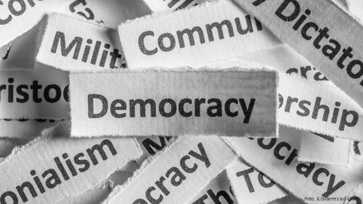 Verschiedene Staatsformen sind auf Zettel geschrieben, die Demokratie liegt über allen