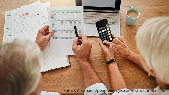 Home budget, finance planning and senior couple calculating their expenses, bills or income during retirement with a calculator, laptop and paper documents from behind. Man and woman discuss savings.