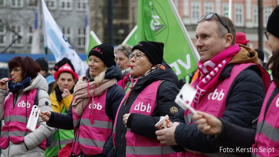 Eine Gruppe Menschen in pinken Warnwesten macht Lärm mit Pfeifen und Rätschen