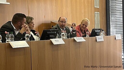 Vier Frauen und zwei Männer sitzen an einem Konferenztisch und diskutieren miteinander