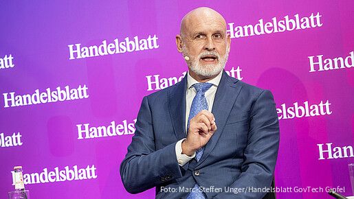 Ein Mann sitzt auf einer Bühne und spricht.