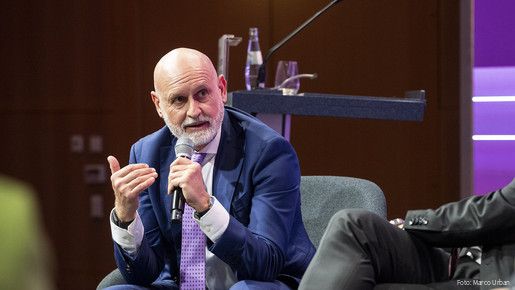 Ein Mann hält ein Mikrofon in der Hand und Diskutiert mit anderen Menschen