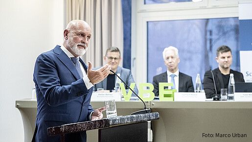 Ein Mann steht hinter einem Rednerpult und spricht in ein Mikrofon