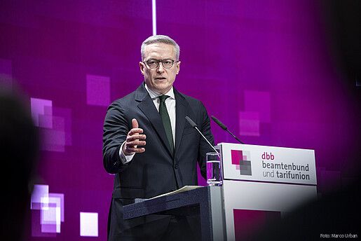 Ein Mann steht auf einer Bühne hinter einem Rednerpult und spricht in ein Mikrofon. Es handelt sich um Karsten Wildberger, Bundesminister für Digitales und Staatsmodernisierung