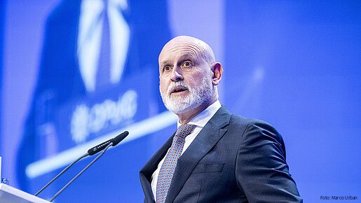 Ein Mann steht hinter einem Rednerpult und spricht in das Mikrofon