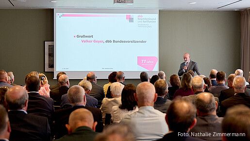 Ein Mann steht hinter einen Rednerpult und spricht in ein Mikrofon.