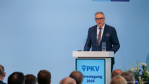 Ein Mann in Anzug steht hinter einem Rednerpult und spricht in ein Mikrofon