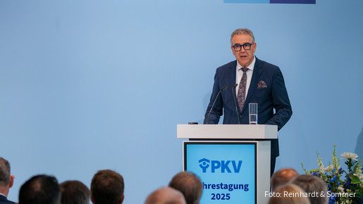 Ein Mann in Anzug steht hinter einem Rednerpult und spricht in ein Mikrofon