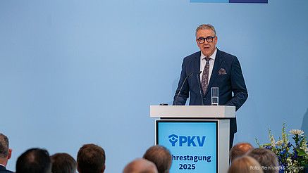 Ein Mann in Anzug steht hinter einem Rednerpult und spricht in ein Mikrofon