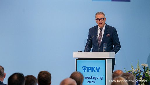Ein Mann in Anzug steht hinter einem Rednerpult und spricht in ein Mikrofon