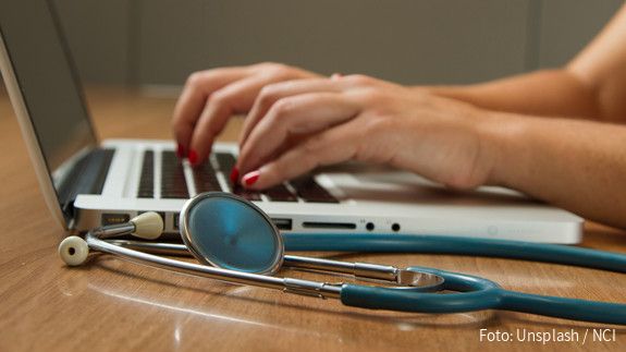 Bürgerversicherung Hände tippen auf Tastatur, davor liegt ein Stethoskop