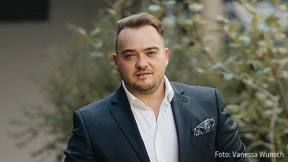Matthäus Fandrejewski, Vorsitzender der dbb jugend, steht in einem begrünten Innenhof.