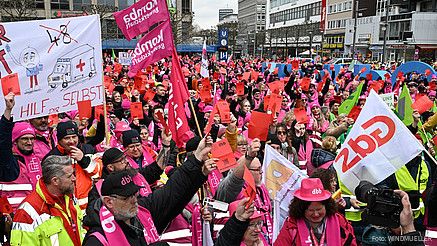Eine Menschenmenge in bunten Warnwesten und Fahnen