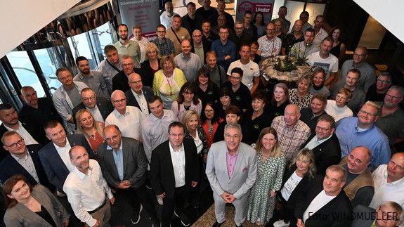 Blick von oben auf eine Menschenmenge, die lächelnd in die Kamera schaut