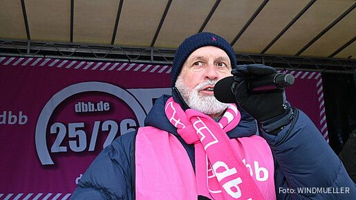 Ein Mann steht auf einer Bühne und spricht in ein Mikrofon