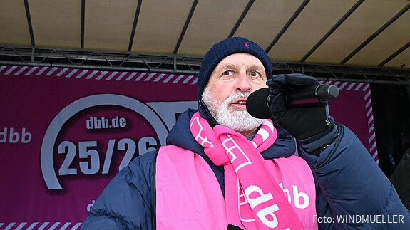 Ein Mann steht auf einer Bühne und spricht in ein Mikrofon