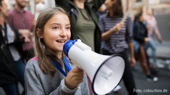 Ein Mädchen spricht auf einer Demonstration in ein Megafon