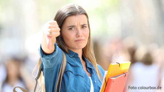 Bildungspolitik: Junge Menschen besser beteiligen Oberschülerin zeigt mit dem Daumen nach untern
