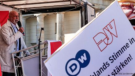 Ein Mann steht hinter einem Rednerpult und spricht in ein Mikrofon