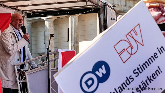 Ein Mann steht hinter einem Rednerpult und spricht in ein Mikrofon