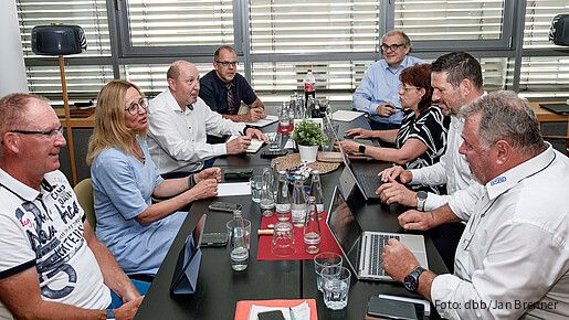 Eine Gruppe Menschen sitzt um einen Besprechungstisch und diskutiert