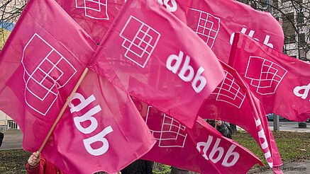 Pinke Fahnen mit dem Logo des dbb beamtenbund und tarifunion wehen im Wind