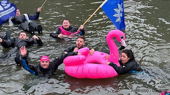 Eine Gruppe Menschen schwimmt in Neoprenanzügen in einem Fluss