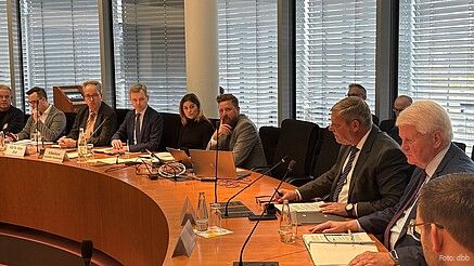 Mehrere Menschen sitzen am runden Tisch und diskutieren.