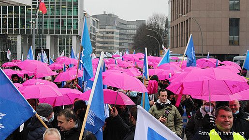 Es ist ein Demozug zu sehen, auf dem viele pinke Regenschirme gespannt wurden.